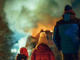 Family standing outside of a burning home