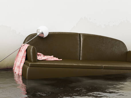 A living room flooded with water high enough to float a couch.